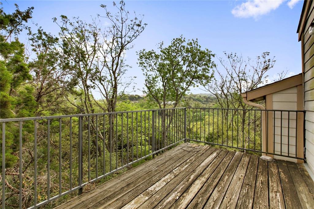 9201 Simmons Road, Unit 117 Austin, TX 78759 - Photo 9 of 11 Wood-finish deck with metal railings and surrounding mature trees