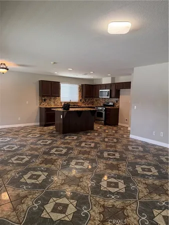 a large kitchen with kitchen island granite countertop a refrigerator and a stove top oven