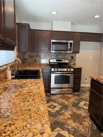 a kitchen with stainless steel appliances granite countertop a stove a sink and a microwave