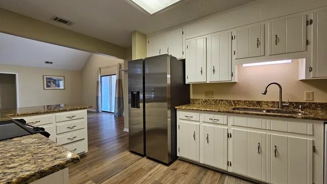 a kitchen with granite countertop a sink stainless steel appliances and cabinets