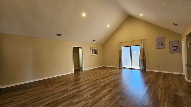a view of an empty room with wooden floor and closet