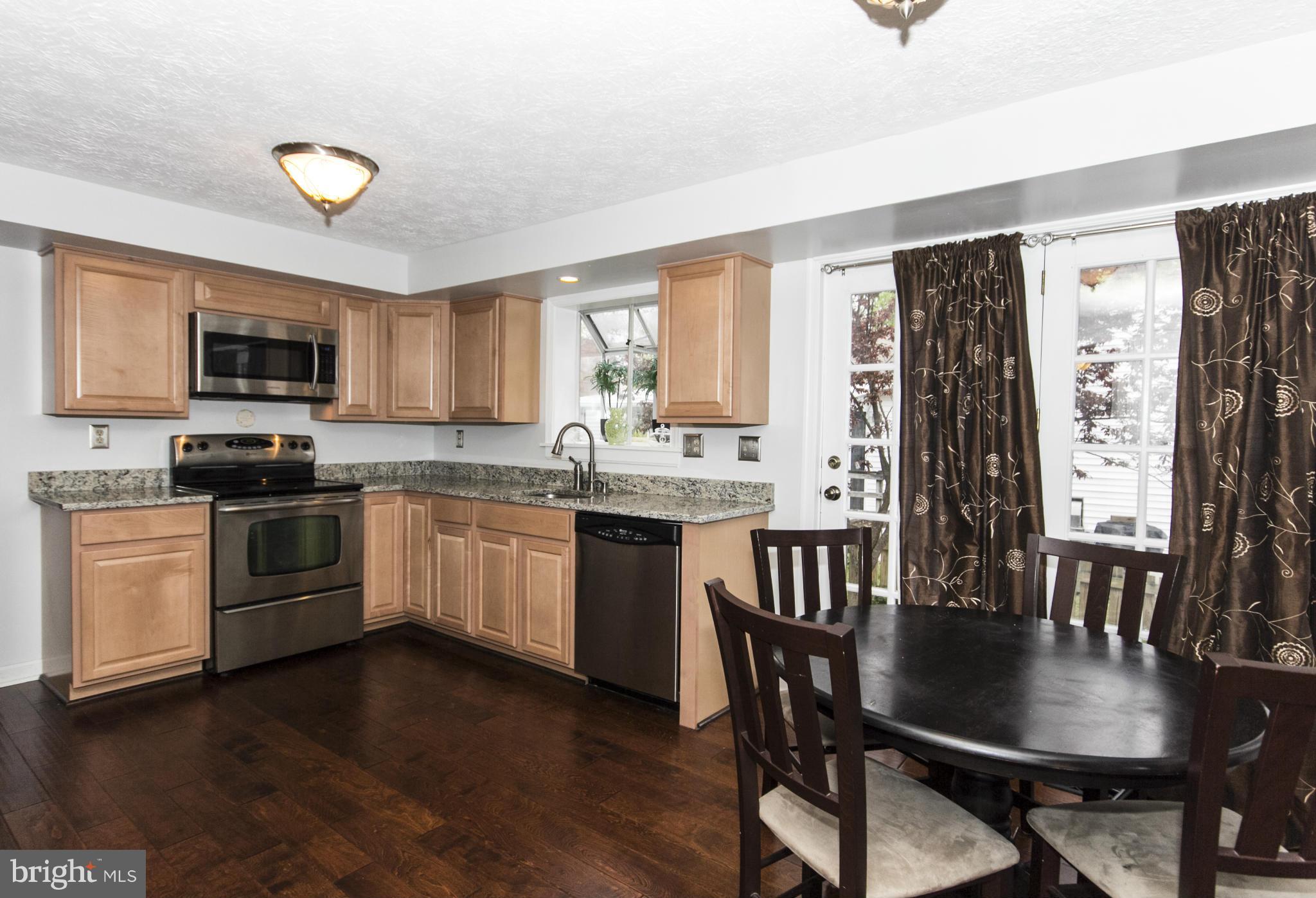 9336 Ramblebrook Road Baltimore, MD 21236 - Photo 5 of 30 a kitchen with granite countertop a stove a sink a dining table and chairs