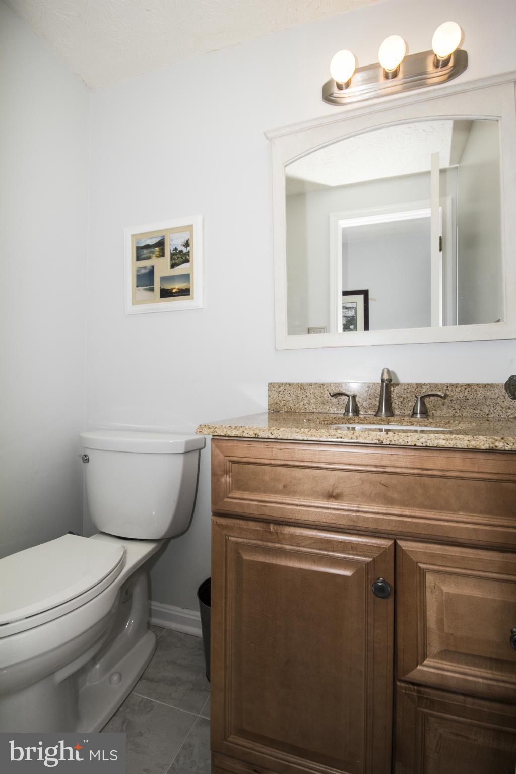 9336 Ramblebrook Road Baltimore, MD 21236 - Photo 9 of 30 a bathroom with a granite countertop toilet sink and mirror