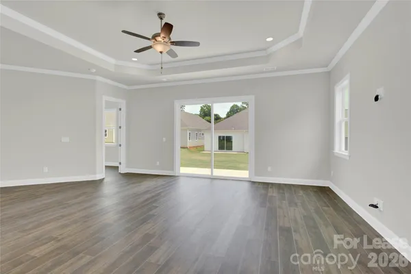a view of an empty room with a window and wooden floor