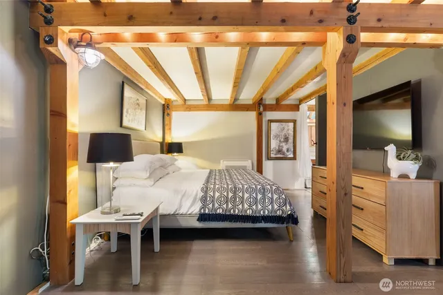 a bedroom with a bed wooden floor and flat screen tv