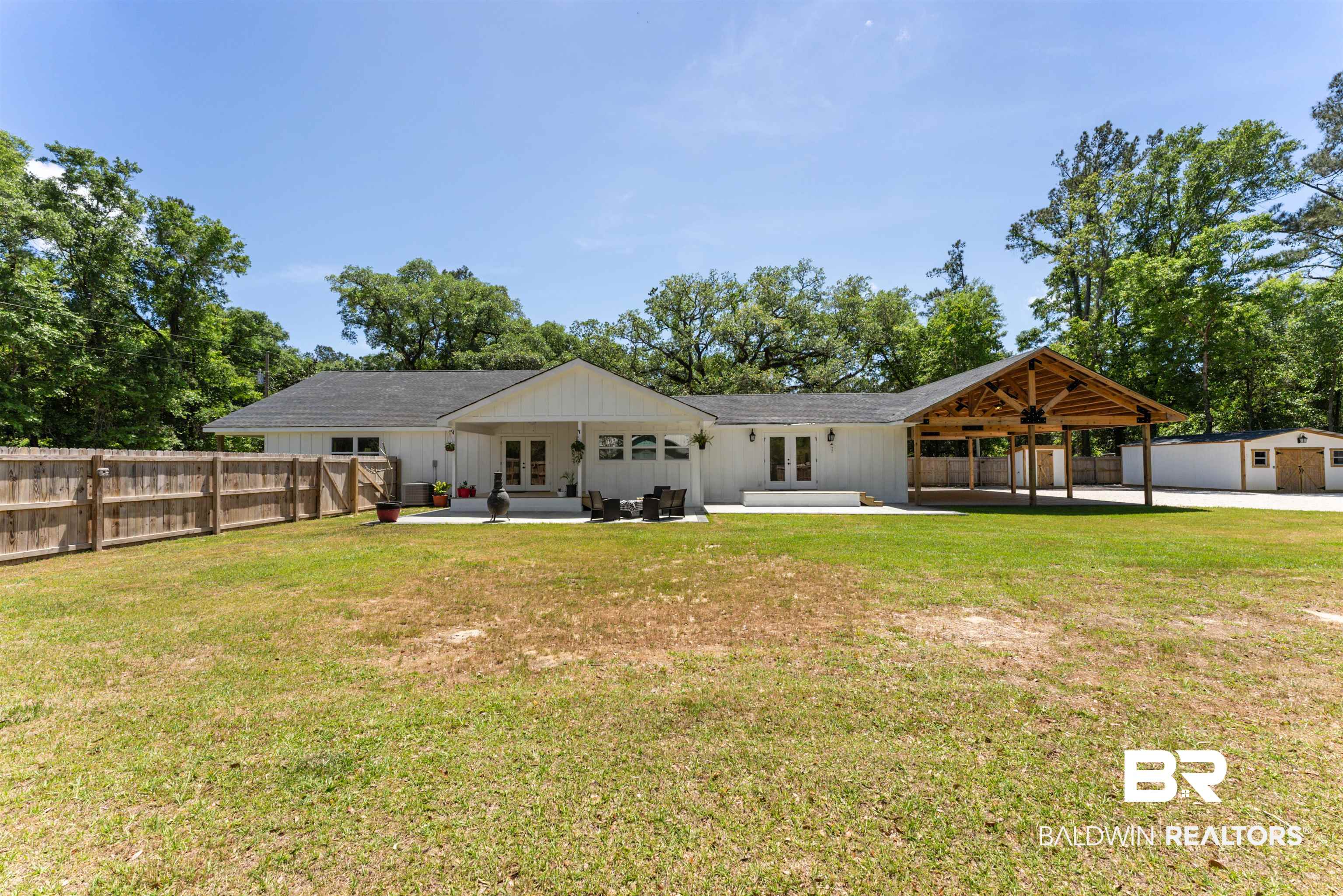 6447 Bemis Lane Bon Secour, AL 36511 - Photo 1 of 62 Expansive backyard featuring a large concrete patio, a covered wooden deck with exposed beams, and a separate storage shed