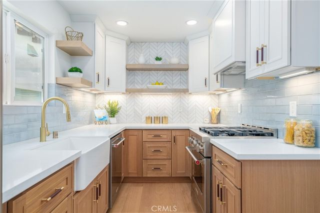 a kitchen with kitchen island granite countertop a sink a stove cabinets and a counter top space