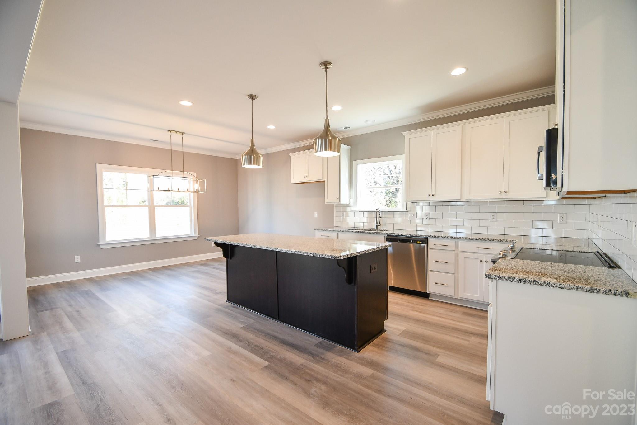 1620 McIntyre Road, Unit 8 Wingate, NC 28174 - Photo 11 of 31 a kitchen with kitchen island granite countertop a sink cabinets and wooden floor