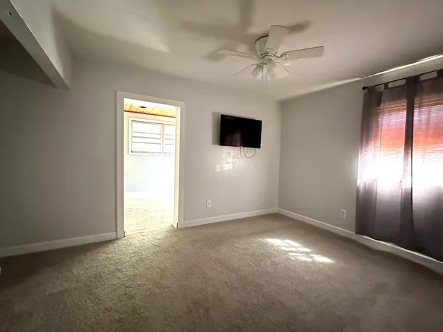 an empty room with a ceiling fan and a window