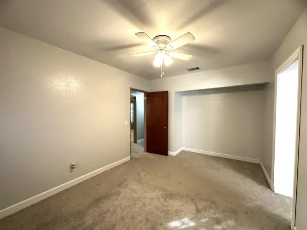 an empty room with closet and a ceiling fan
