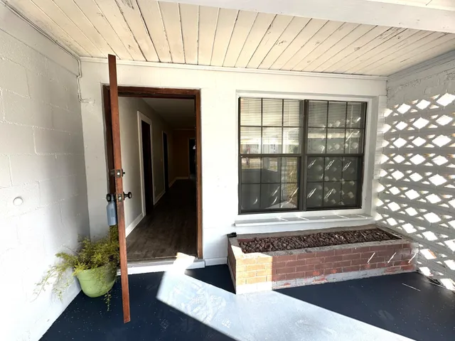 a view of a hallway with wooden floor and a bathroom