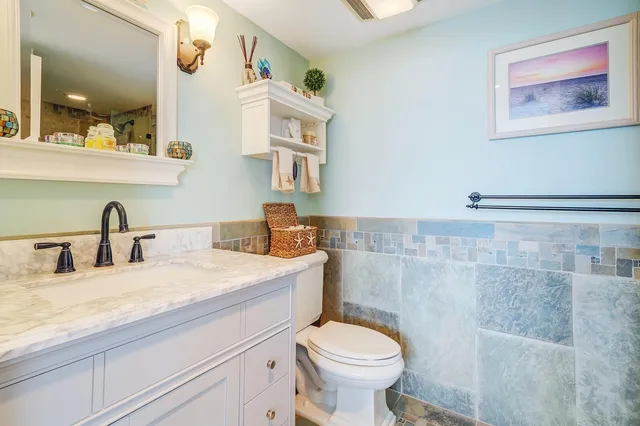 a bathroom with a granite countertop sink mirror vanity and toilet