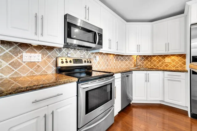 a kitchen with granite countertop white cabinets stainless steel appliances and a sink