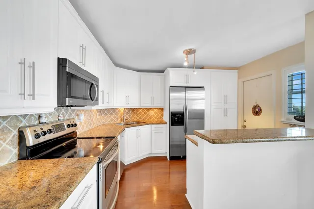 a kitchen with stainless steel appliances granite countertop a refrigerator a stove top oven a sink and dishwasher