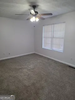 an empty room with a chandelier fan and windows