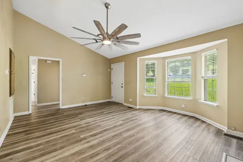 a view of an empty room with a window and wooden floor