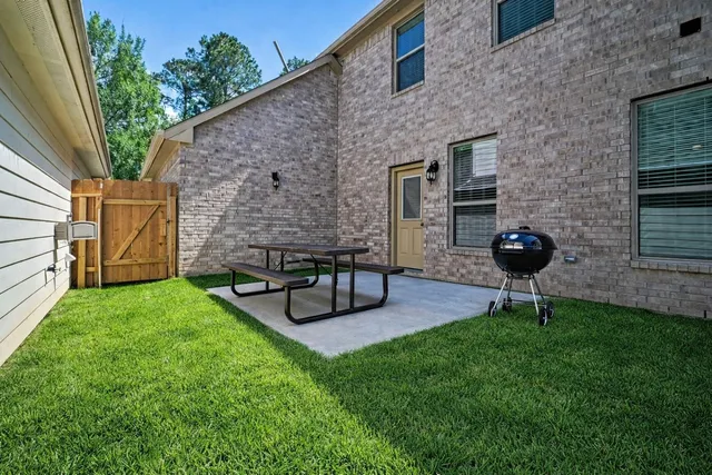 a view of a backyard with table and chairs potted plants and a brick wall