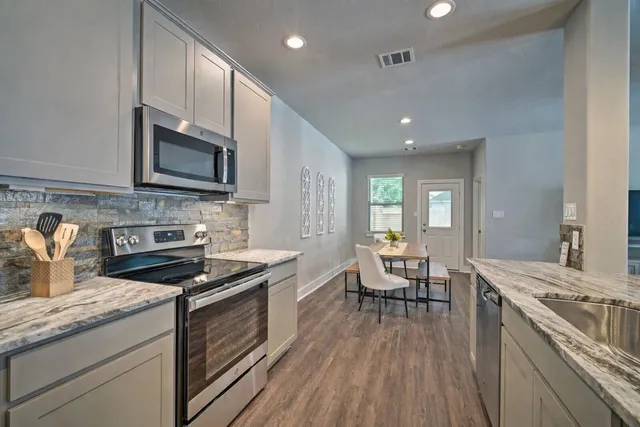 a kitchen with granite countertop wooden floors a stove and white stainless steel appliances