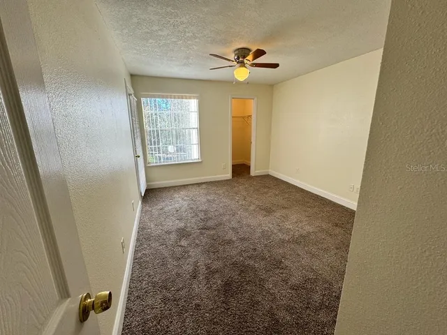 an empty room with windows and fan