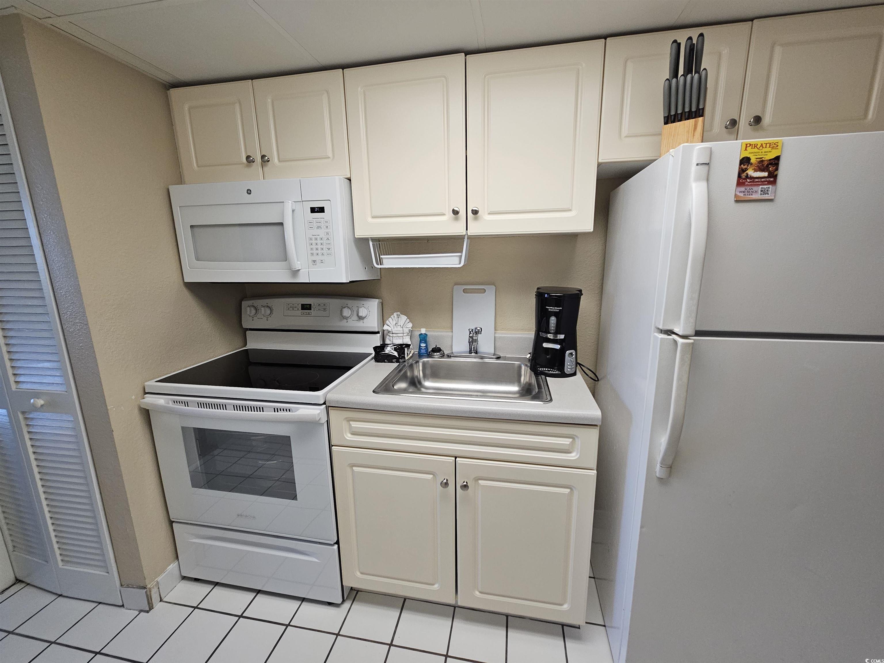 201 77th Avenue North, Unit 1025 Myrtle Beach, SC 29572 - Photo 7 of 36 Kitchen with white appliances, white cabinetry, light tile patterned floors, and light countertops