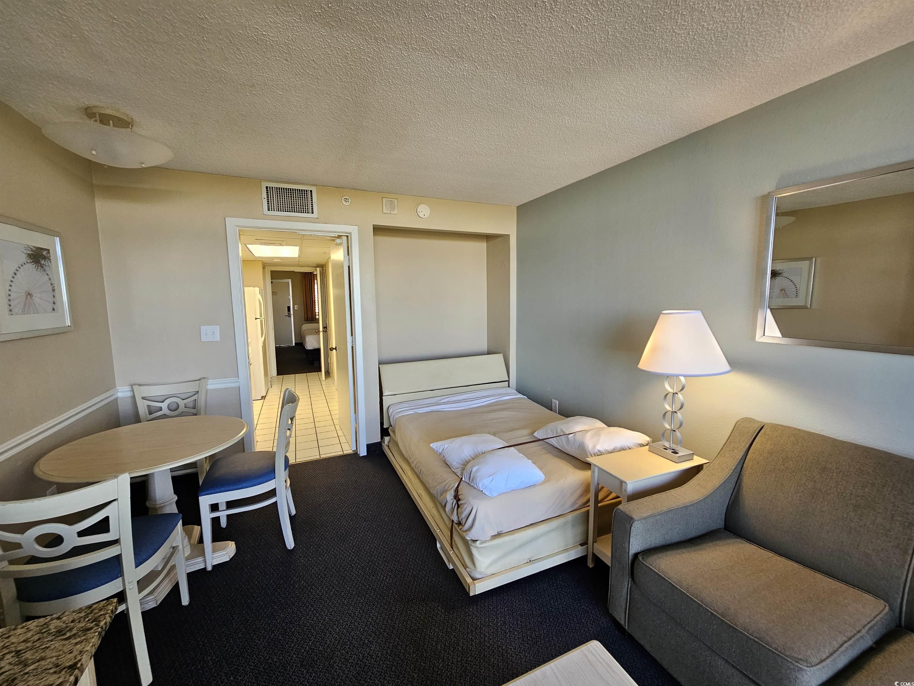 201 77th Avenue North, Unit 1025 Myrtle Beach, SC 29572 - Photo 10 of 36 Bedroom featuring a textured ceiling, carpet flooring, and freestanding refrigerator