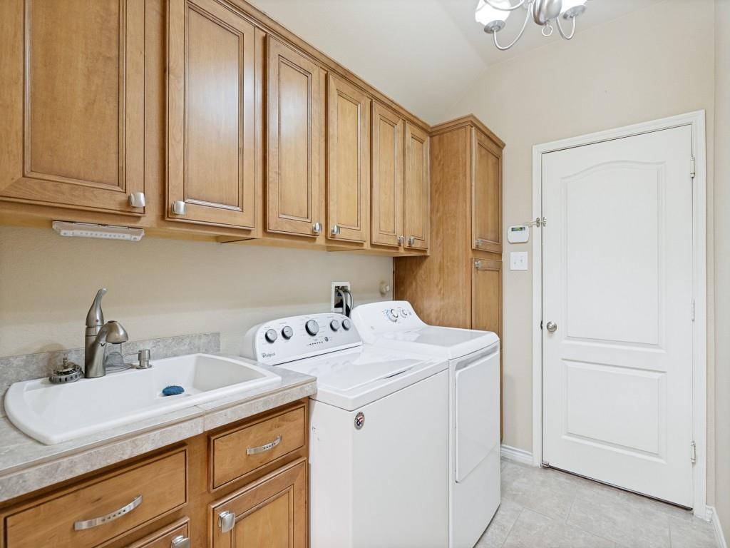 10032 Bell Rock Road Frisco, TX 75035 - Photo 20 of 23 Utility room featuring wood-finish cabinetry, a utility sink with a brushed nickel faucet, a tall built-in storage cabinet, and light-colored flooring.
