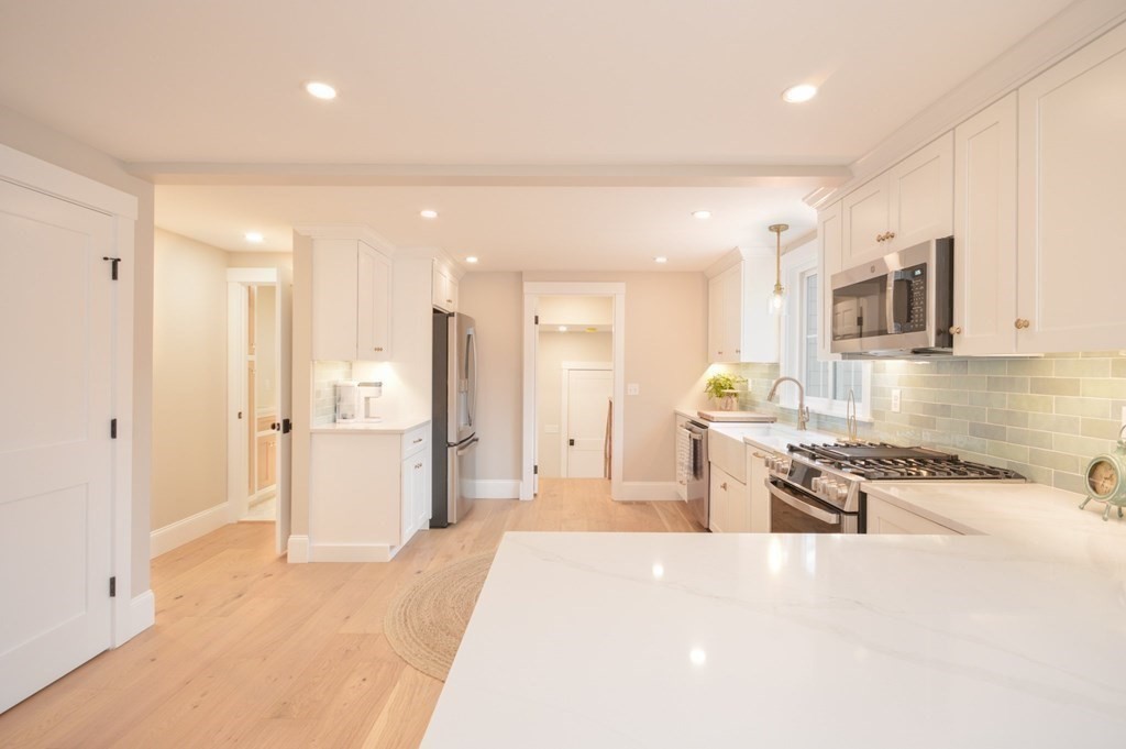 52 Uncle Barneys Road Dennis, MA 02670 - Photo 6 of 42 a large white kitchen with stainless steel appliances kitchen island granite countertop a refrigerator and a sink