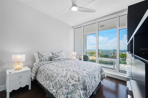 a bedroom with a large bed and a chandelier next to a window