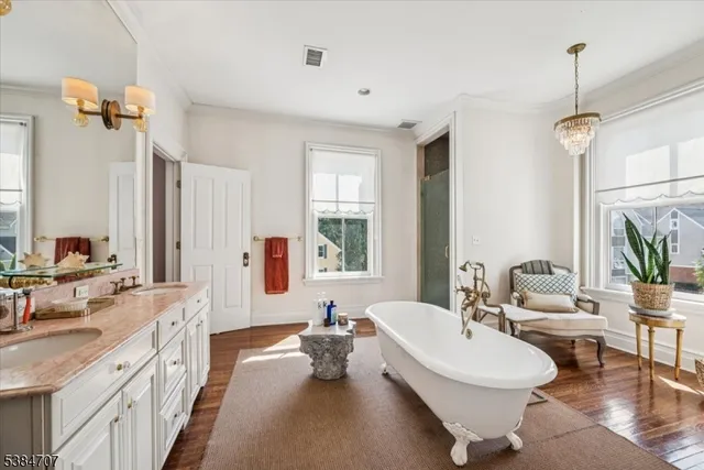 a spacious bathroom with a double vanity sink a mirror a bathtub and a window