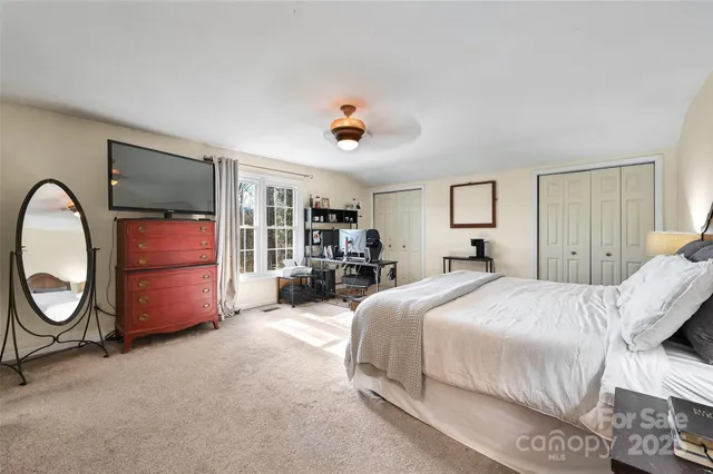 a spacious bedroom with a bed a dresser and mirror