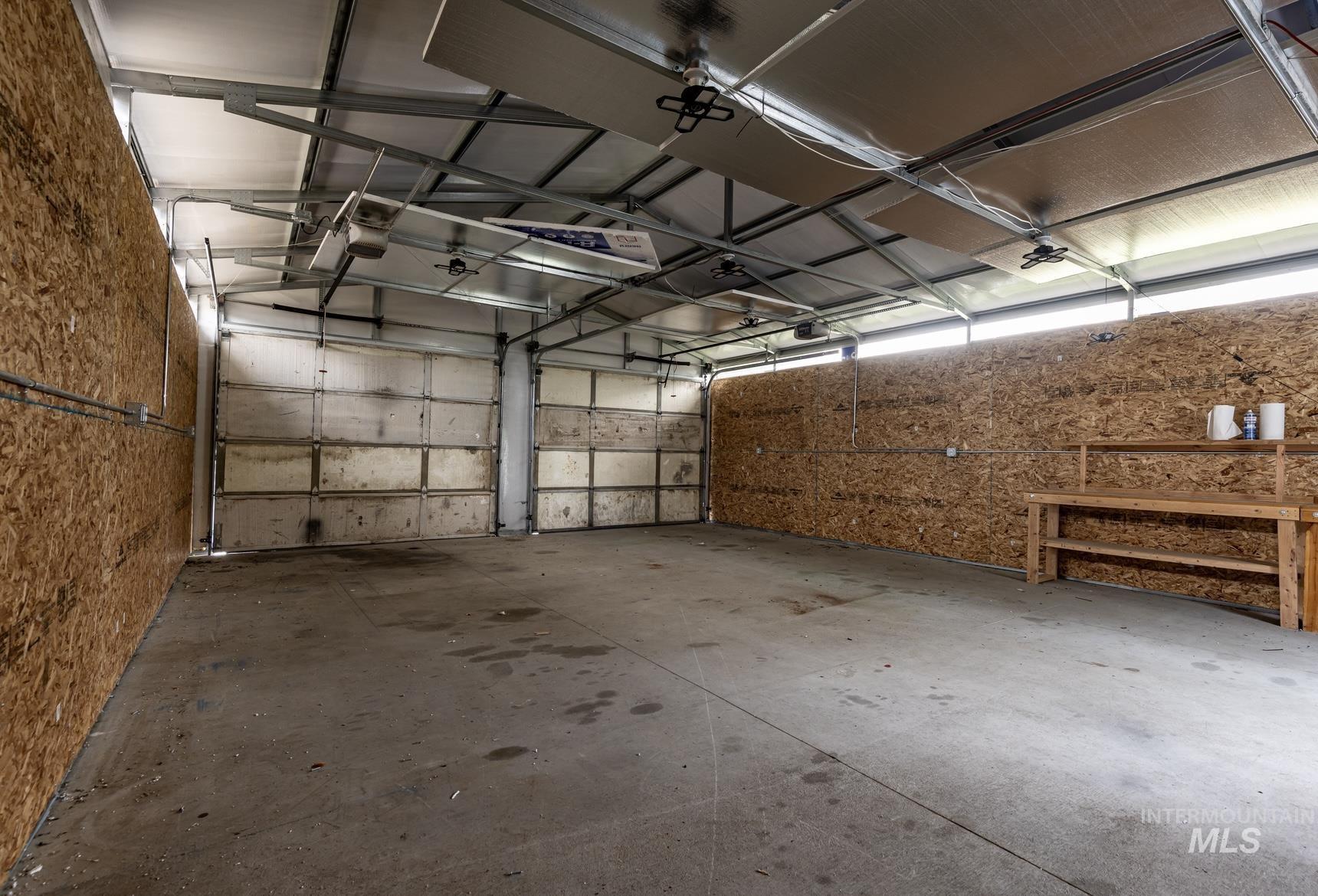 17028 Lower Pleasant Ridge Road Caldwell, ID 83607 - Photo 19 of 21 Spacious garage featuring two overhead doors, concrete flooring, exposed metal ceiling beams, and oriented strand board walls