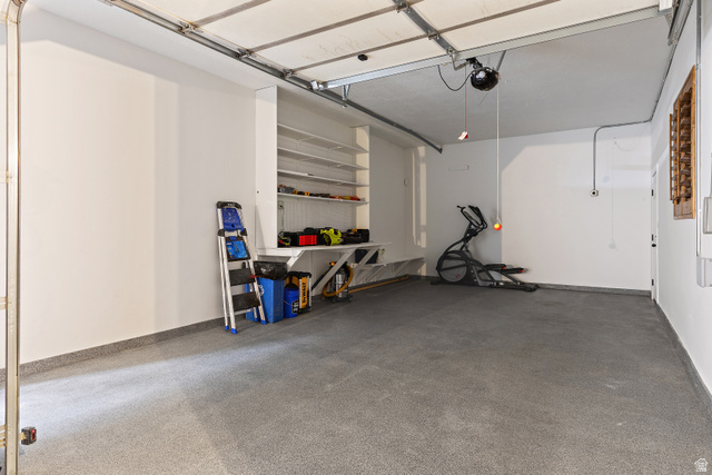 912 North Loafer Canyon Road Elk Ridge, UT 84651 - Photo 77 of 98 Spacious garage with an epoxy-coated floor, built-in shelving, a workbench, and a white overhead garage door