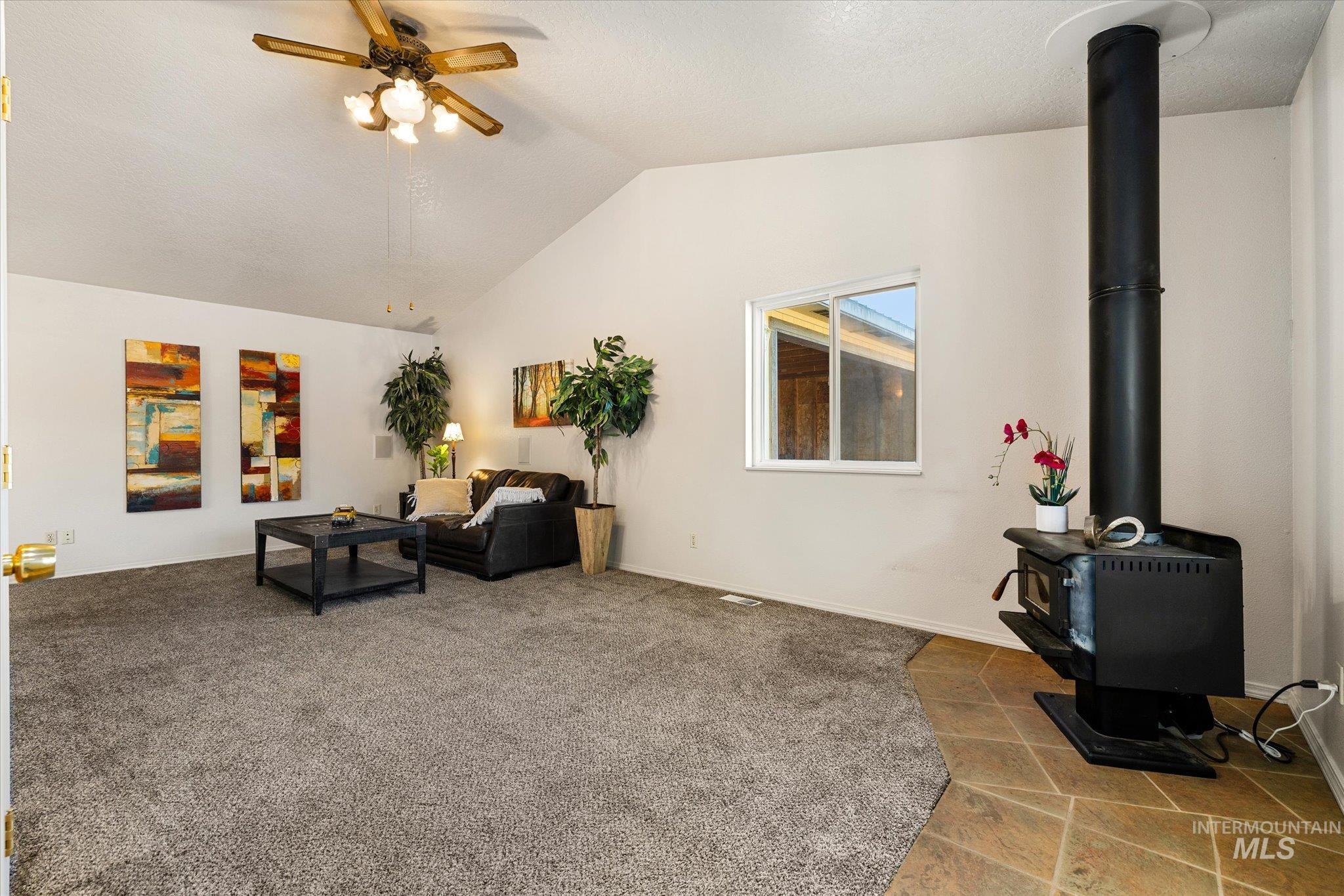 9820 Highway 44 Middleton, ID 83644 - Photo 13 of 50 Living room featuring ceiling fan, a wood stove, and carpet floors
