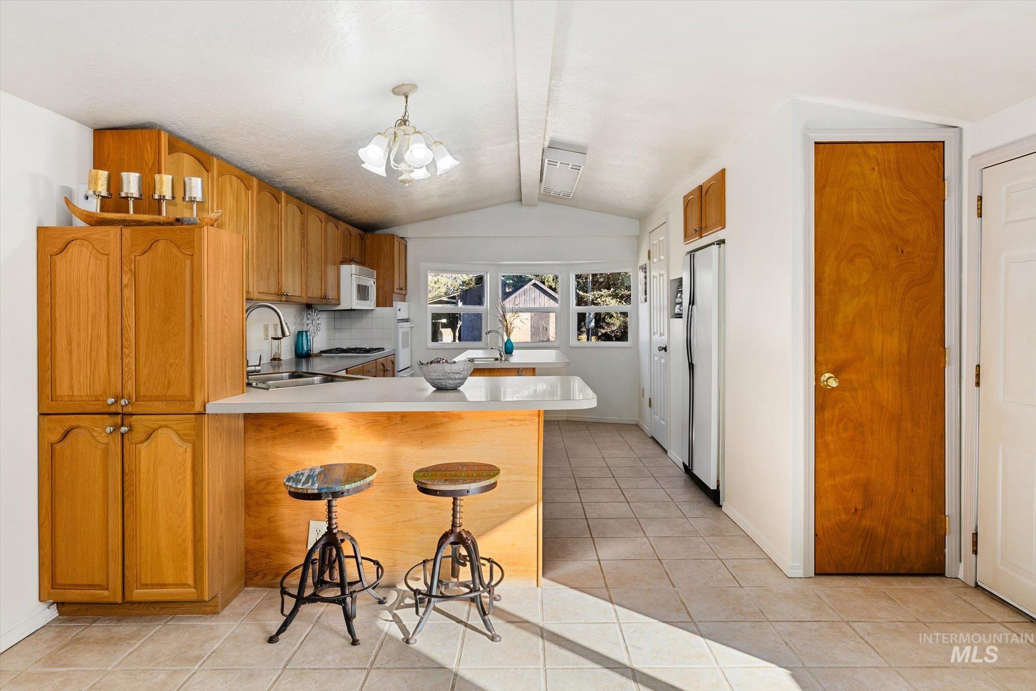 9820 Highway 44 Middleton, ID 83644 - Photo 20 of 50 Kitchen with light countertops, a breakfast bar, decorative backsplash, a peninsula, and wood finish cabinetry