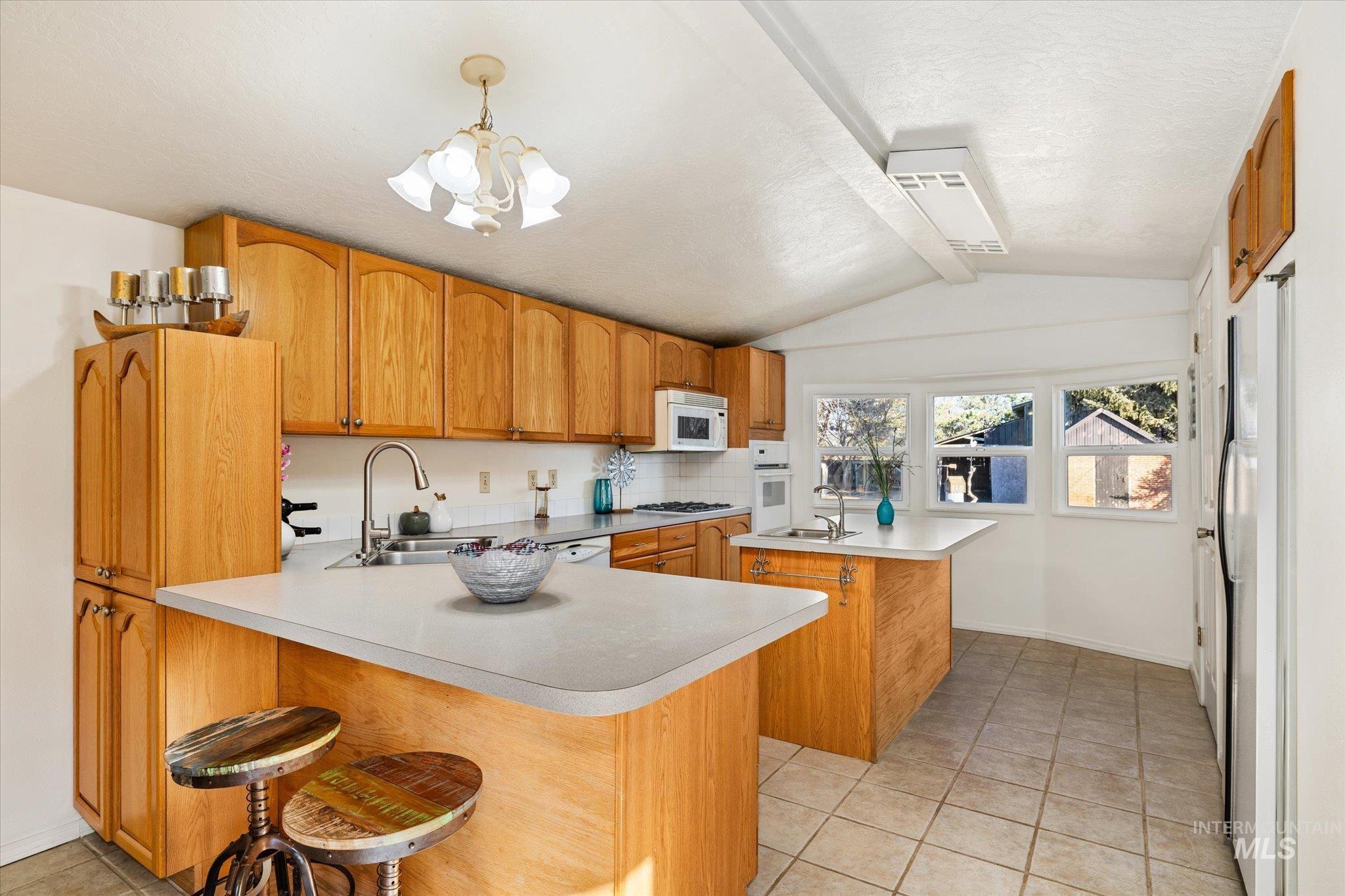 9820 Highway 44 Middleton, ID 83644 - Photo 21 of 50 Kitchen with a center island with sink, light tile patterned floors, a breakfast bar area, a textured ceiling, and light countertops