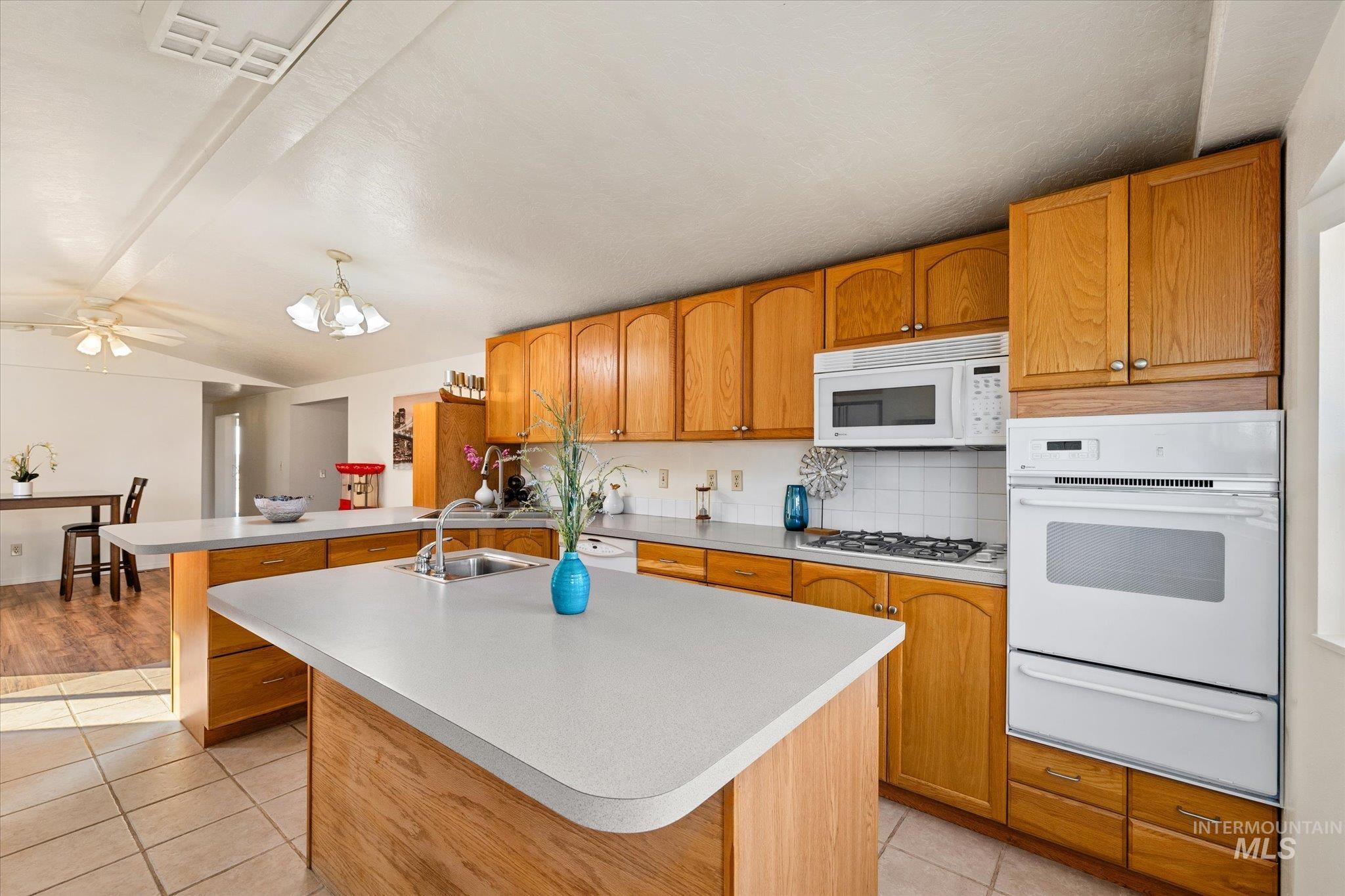 9820 Highway 44 Middleton, ID 83644 - Photo 23 of 50 Kitchen featuring white appliances, a warming drawer, light tile patterned flooring, tasteful backsplash, and light countertops