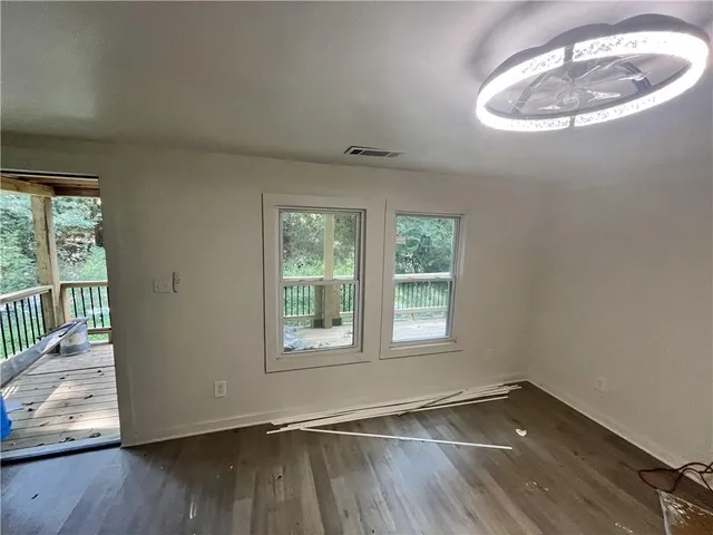 an empty room with wooden floor and windows