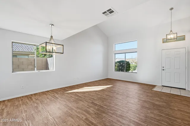 a view of an empty room with wooden floor and windows