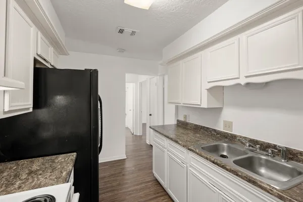 a kitchen with stainless steel appliances granite countertop a refrigerator a sink and white cabinets