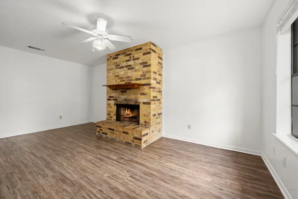 an empty room with wooden floor fireplace and window
