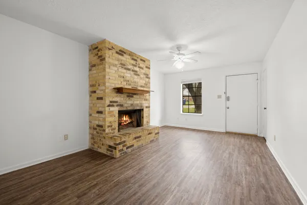 an empty room with windows fireplace and wooden floor