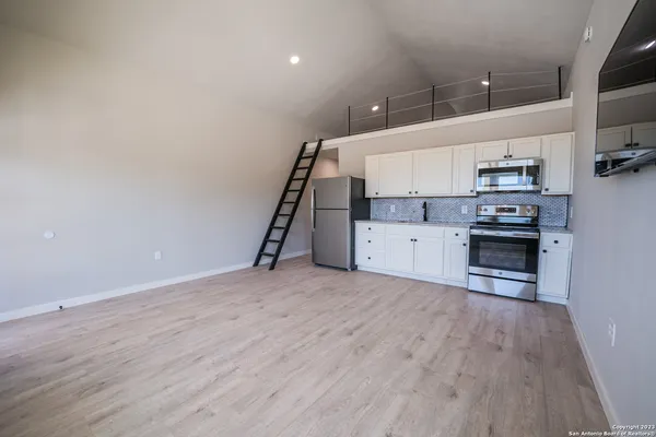 an empty room with wooden floor and electronic appliances