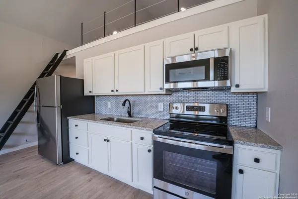 a kitchen with stainless steel appliances granite countertop a stove a microwave and a hard wood floors