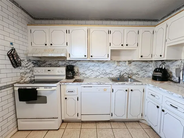 a kitchen with white cabinets and white appliances