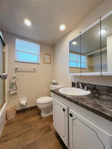 a bathroom with a granite countertop sink a toilet and a mirror