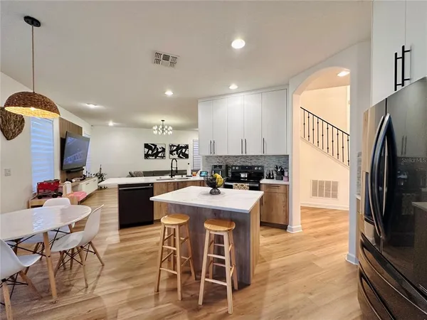 a kitchen with stainless steel appliances granite countertop a refrigerator a stove a sink a dining table and chairs with wooden floor