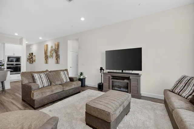 a living room with furniture a large window and wooden floors