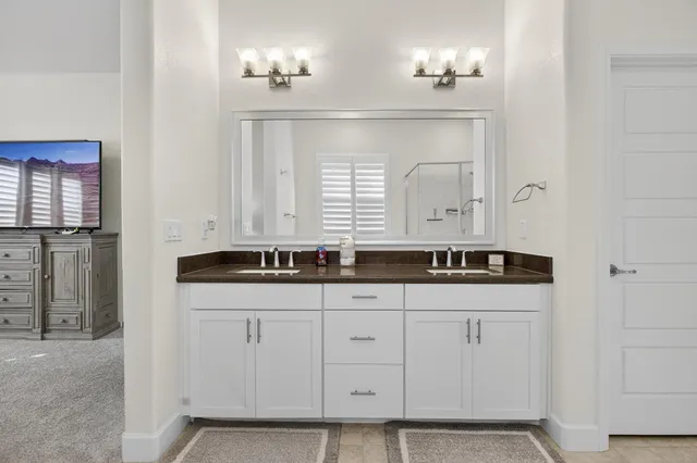 a en suite spacious bathroom with a tub double vanity and windows