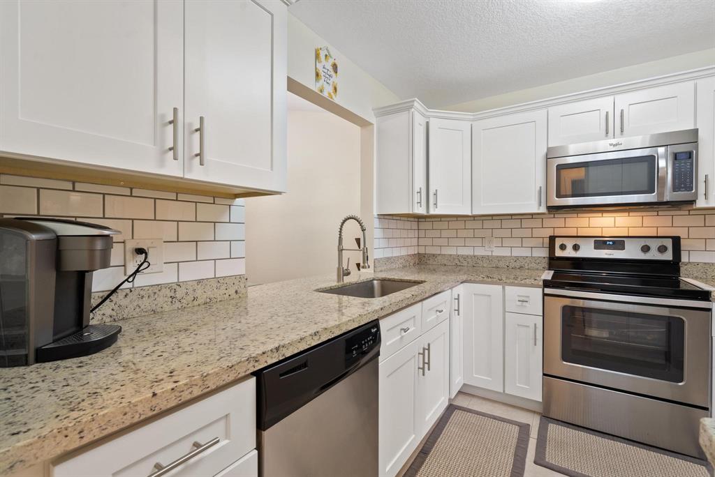 6734 Bridlewood Court, Unit 6734 Boca Raton, FL 33433 - Photo 12 of 42 a kitchen with granite countertop a sink stainless steel appliances and cabinets