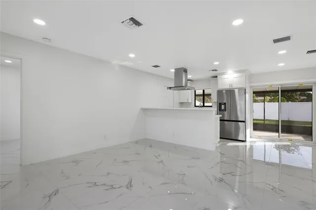 a view of a kitchen with refrigerator and an empty room